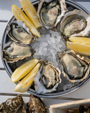 Fresh oysters on ice with lemon wedges in a round tin