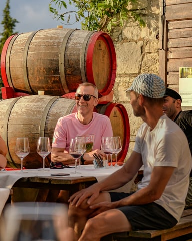 People enjoying wine tasting at a winery with oak barrels