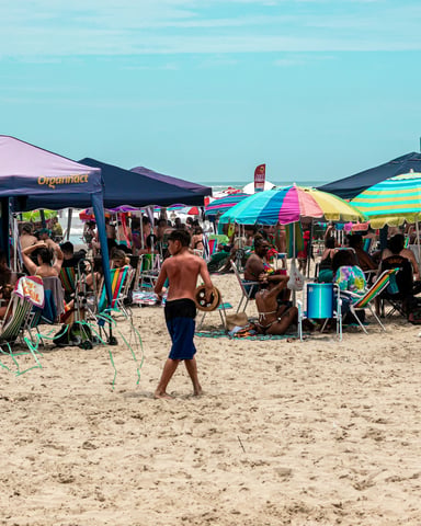 Crowd enjoying a sunny beach festival with colorful tents