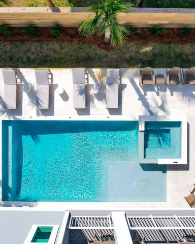 Aerial view of a private pool with lounge chairs and palm trees