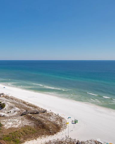 Beachfront high-rise condominiums overlooking white sand beach and turquoise ocean with waves