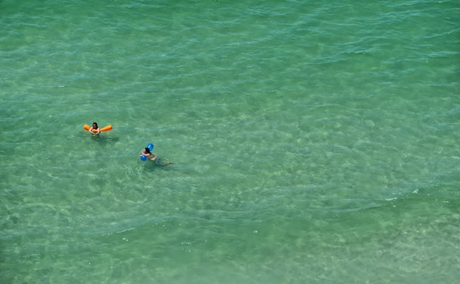 Aerial view of two people swimming in emerald green Gulf water