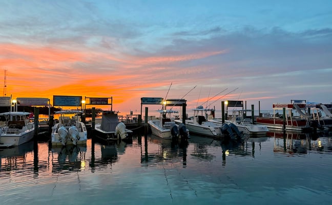 Boats docked in a Florida marina at a vivid orange and pink sunset